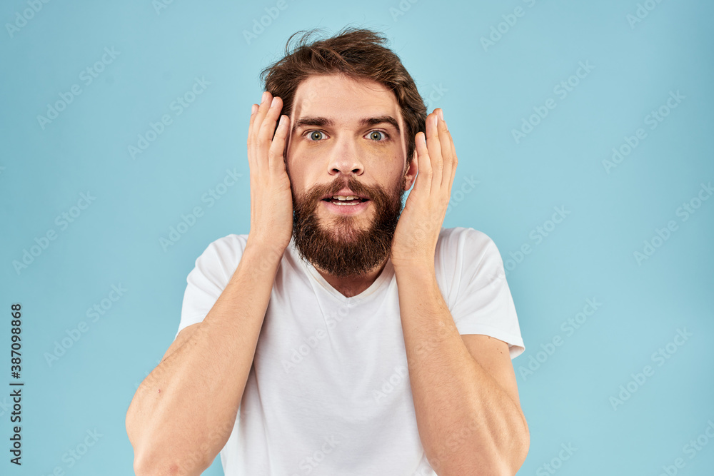 Fototapeta premium Emotional man with a beard in a white t-shirt blue background fun lifestyle