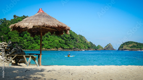 Beach with umbrellas and boat in the water. The Indonesian island of Java