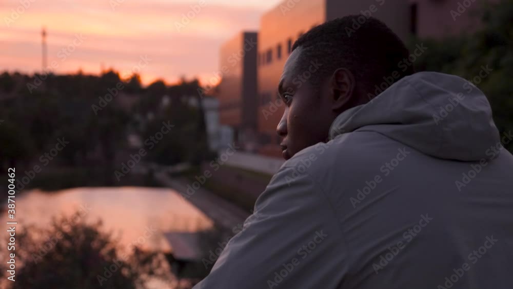 Close-up of young black runner man resting and looking at the horizon in a city park at dusk. African american male athlete in sportswear outdoor. Close-up of young black runner man resting and looking at the horizon in a city park at dusk. African american male athlete in sportswear outdoor.