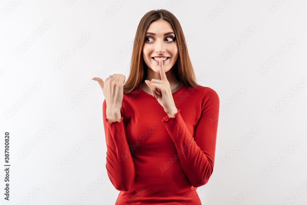 Image of young happy woman smiling and pointing thumb aside, shows place for ad Image of young happy woman smiling and pointing thumb aside, shows place for ad