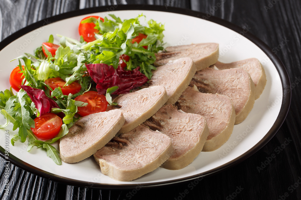 Cold appetizer of beef tongue with fresh salad close-up in a plate on the table. horizontal Cold appetizer of beef tongue with fresh salad close-up in a plate on the table. horizontal