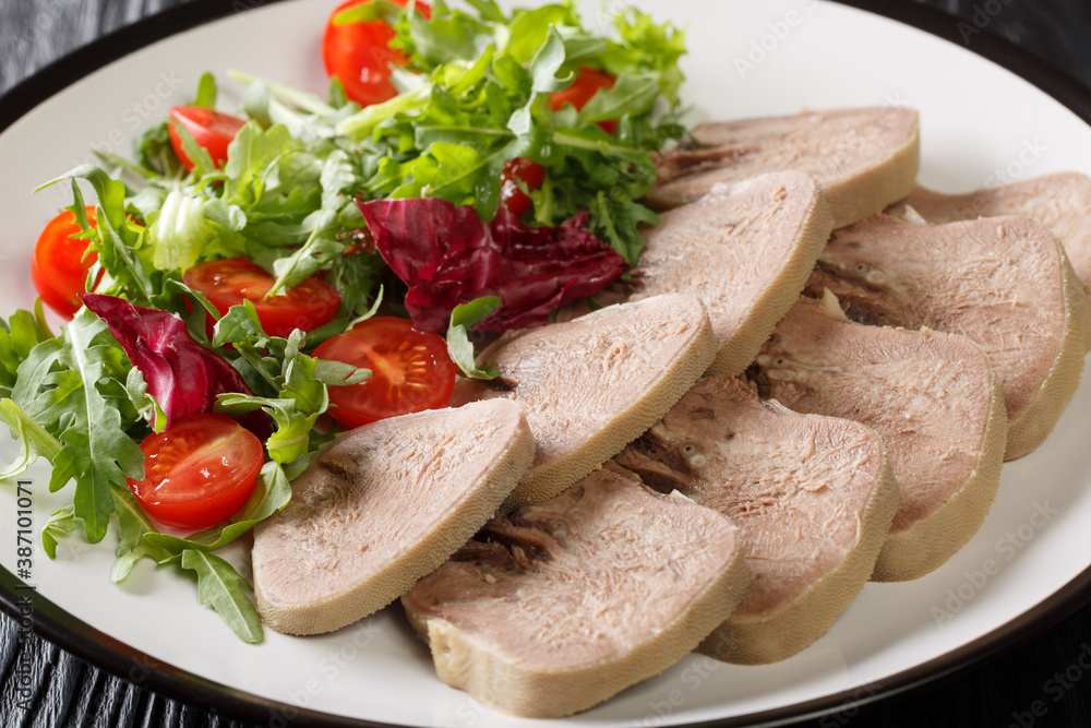 Delicious delicacy of beef tongue with fresh salad close-up in a plate on the table. horizontal