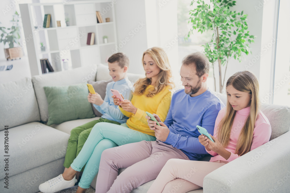 Photo of family people sit couch mom dad and two little kids read social network news on cellphone in house indoors