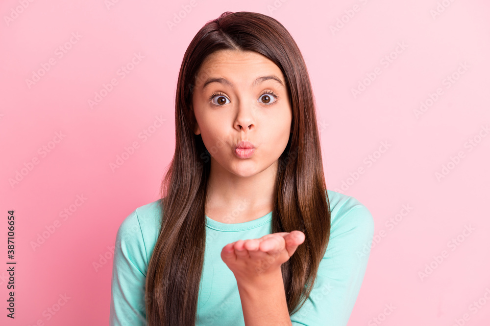 Photo of cute lovely little latin lady long hairstyle hold hand arm pouted lips send air kiss you wide open eyes wear casual turquoise teal sweatshirt isolated pink color background