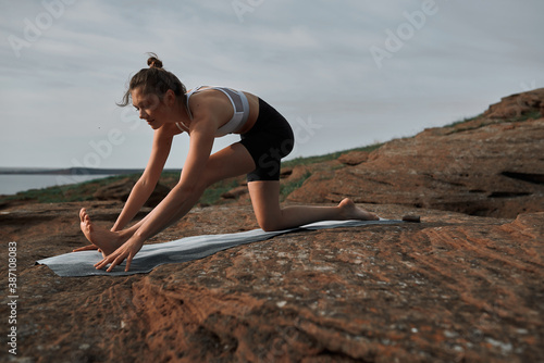 young beautiful cute blonde is engaged in yoga in the mountains in the light of the sun, the concept of a healthy lifestyle. the gymnast stands in the pose of a child salamba