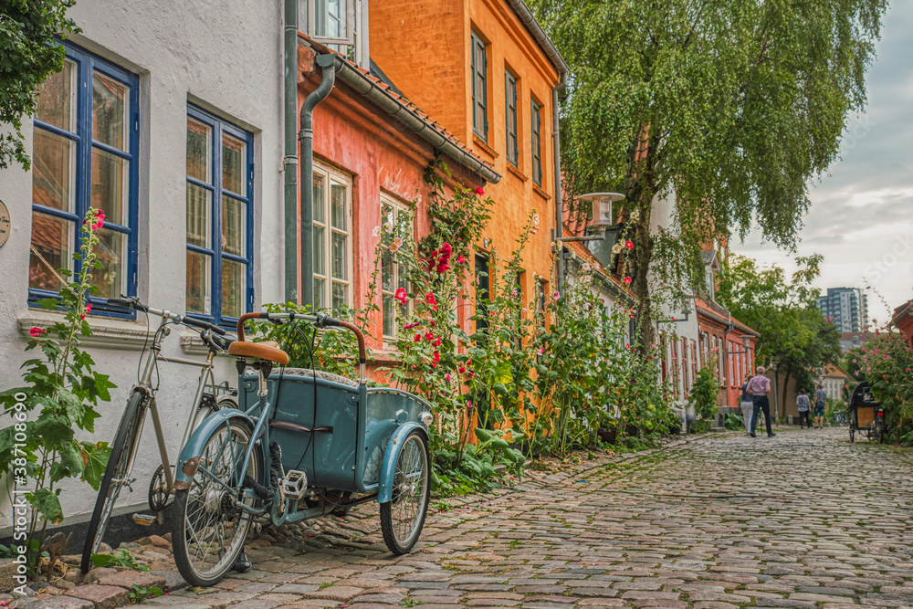 On a summer day a typical Danish Cargo bike, better known as Christiania Bike, is parked at the entrance of a house in a cosy, cobbled street conveying coziness and cultural concept - Aarhus, Denmark