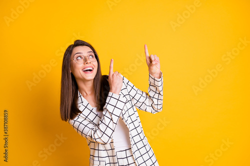 Photo of amazed business woman dressed checkered blazer pointing looking empty space two fingers isolated yellow color background photo