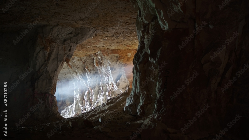 Photo of the cave. Darkness, pierced by a ray of light. Frightening atmosphere.