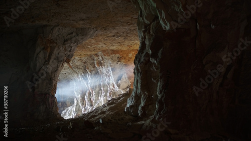 Photo of the cave. Darkness, pierced by a ray of light. Frightening atmosphere.