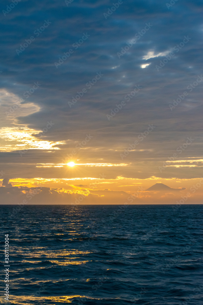 雲間の夕日に煌めく波と夕映えの富士