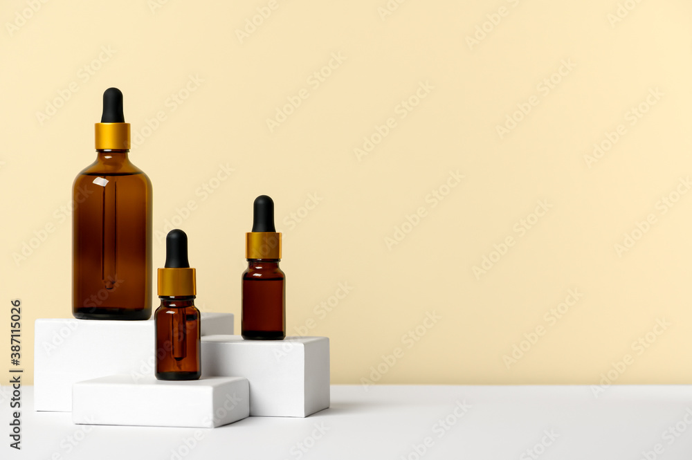 Composition brown glass bottles with aromatic natural essential oil. Cosmetic product on white geometric podium. Alternative medicine, natural therapy. Packaging for beauty fragrance skincare product Composition brown glass bottles with aromatic natural essential oil. Cosmetic product on white geometric podium. Alternative medicine, natural therapy. Packaging for beauty fragrance skincare product