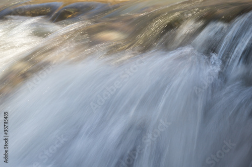 Petite cascade dans une rivi  re qui scintille au soleil