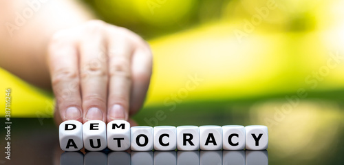 Foto Hand turns dice and changes the word autocracy to democracy.