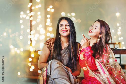 Beautiful Indian women in festive outfit posing as best friends, laughing over a nice bokeh background