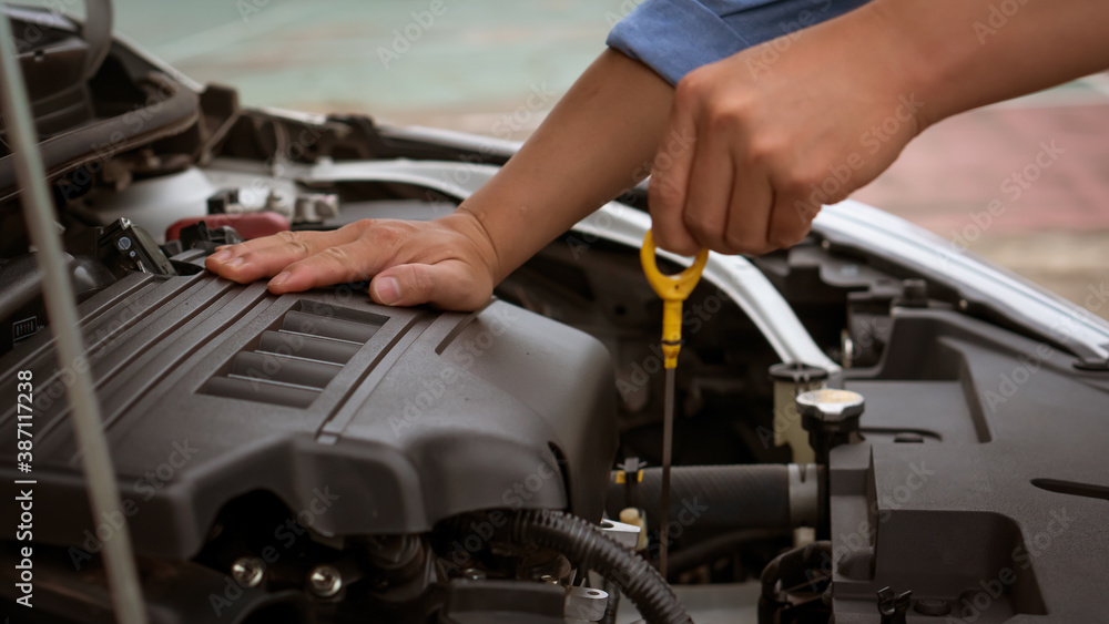 The young man's hand was measuring the level of his car oil. The young man's hand was measuring the level of his car oil.