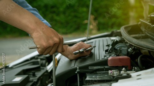 Young man's hand was repairing a car with a wrench in hand, the car was broken on the way.