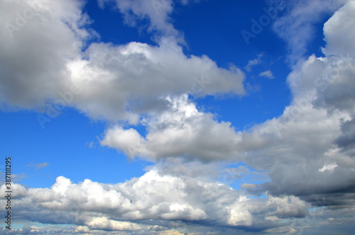 Blue sky with scenic cumulonimbus clouds. Natural blue background with clouds.