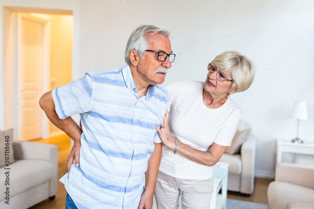 Obraz premium Senior couple at home.Elderly man is having back pain and his lovley wife supports him.