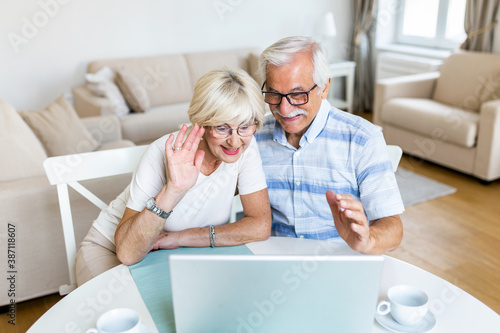 Senior couple is talking online via video connection on the laptop. Having nice time withfriends and family via video call. photo