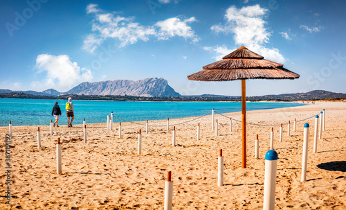 Sunny spring view of La Cinta beach with Tavolara island on background. Tourists walks on the shore of Mediterranean sea. Picturesqaue morning scene of Sardinia island, Italy, Europe. photo