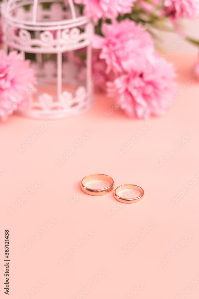 Gold wedding rings on a pink floral background