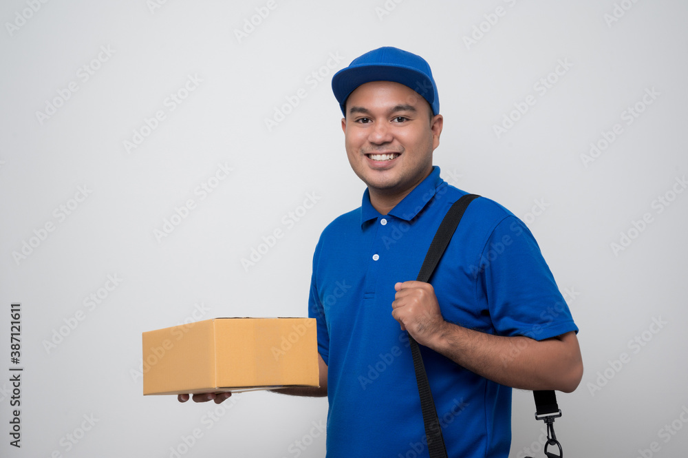 Young smiling asian delivery man in blue uniform holding messenger bag standing on isolated white background. Young smiling asian delivery man in blue uniform holding messenger bag standing on isolated white background.