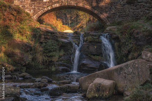 Three Shire Heads. An autumnal waterfall and stone packhorse bridge at Three Shires Head in the Peak District.