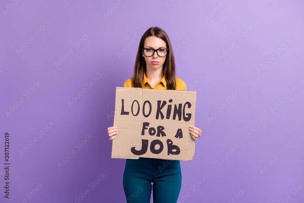 Photo portrait of jobless girl keeping carton placard searching for work isolated on vivid purple color background Photo portrait of jobless girl keeping carton placard searching for work isolated on vivid purple color background