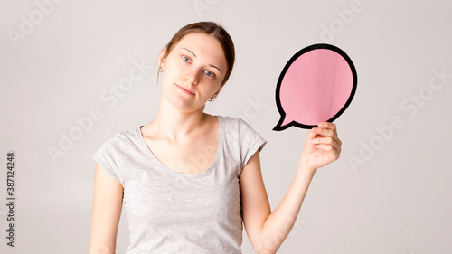 mid adult woman holding blank speech bubble on white background. Horizontal shape, front view, waist up, copy space