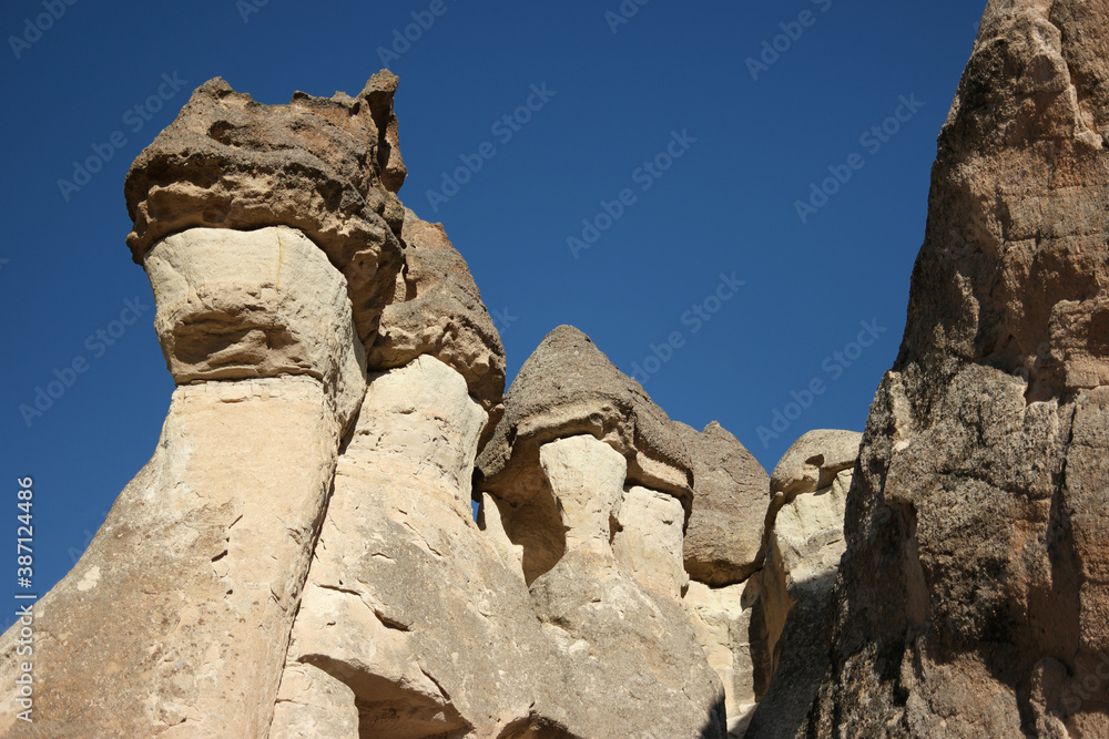 Fairy chimneys and cave dwellings in Cappadocia, Turkey. Huge rock formations in ancient cave city. Blue sky in the background.