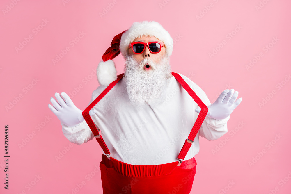 Photo of astonished overweight santa claus impressed tradition x-mas christmas shopping sales news pull suspenders wear headwear overalls sunglass isolated pink color background - obrazy, fototapety, plakaty 
