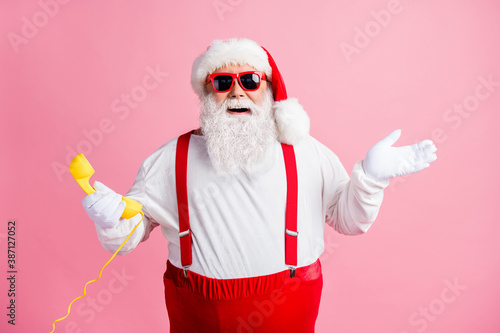 Portrait of his he nice attractive cheerful cheery glad Santa father talking on yellow phone contact center communication ho-ho holly jolly isolated over pink pastel color background