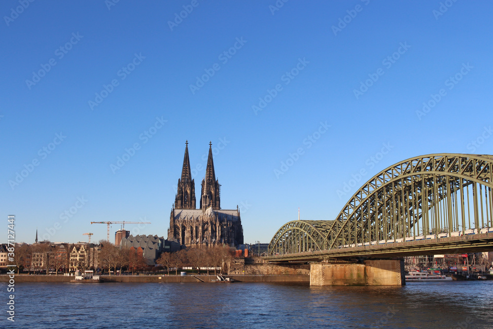 Fototapeta premium The Hohenzollern bridge over Rhine river on a sunny day. The Cologne Cathedral (Kolner Dom) in the city of Cologne, Germany. It is the largest Gothic church in northern Europe.