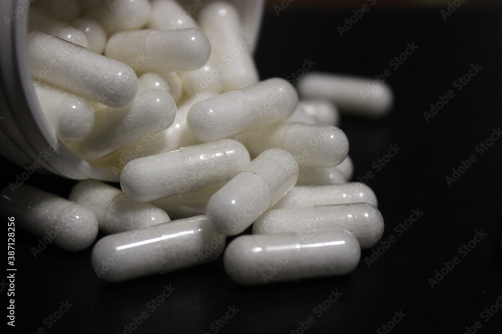 Close up of some white drug capsules on a black background Close up of some white drug capsules on a black background