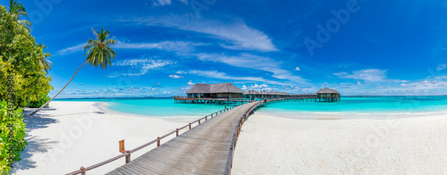 Amazing beach panorama at Maldives. Luxury resort villas seascape with paradise island coast. Beautiful blue sky and white clouds. Beautiful beach background for vacation holiday. 