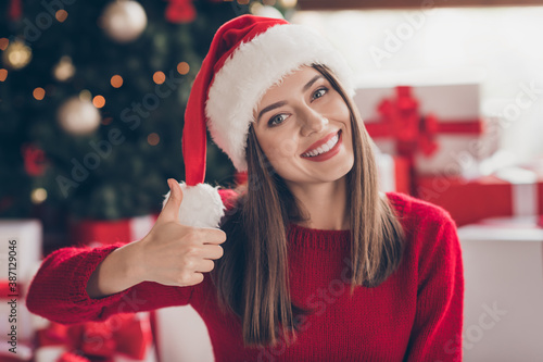 Fotografie Pretty woman raise hand resent thumb up toothy smile wear santa headwear red swe