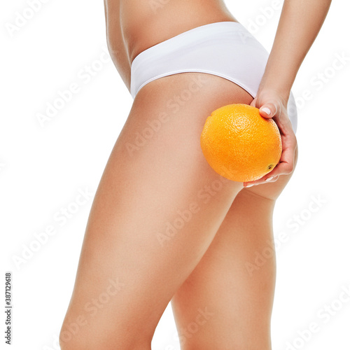 studio shot of attractive young woman with beautiful body holding orange isolated on white
