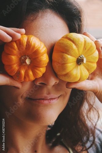 Portrait of a young woman smiling with small pumpkins on her face photo