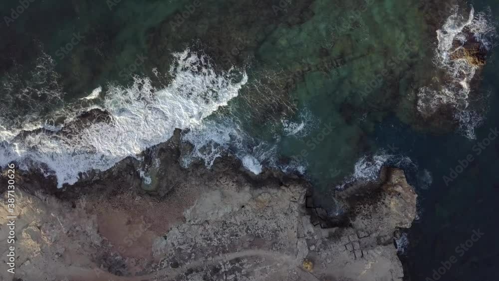 Aerial top down view of ocean sea waves splashing with white foam against rocks, rocky cliff, island Crete, Greece. Spinning zoom out footage. Aerial top down view of ocean sea waves splashing with white foam against rocks, rocky cliff, island Crete, Greece. Spinning zoom out footage.