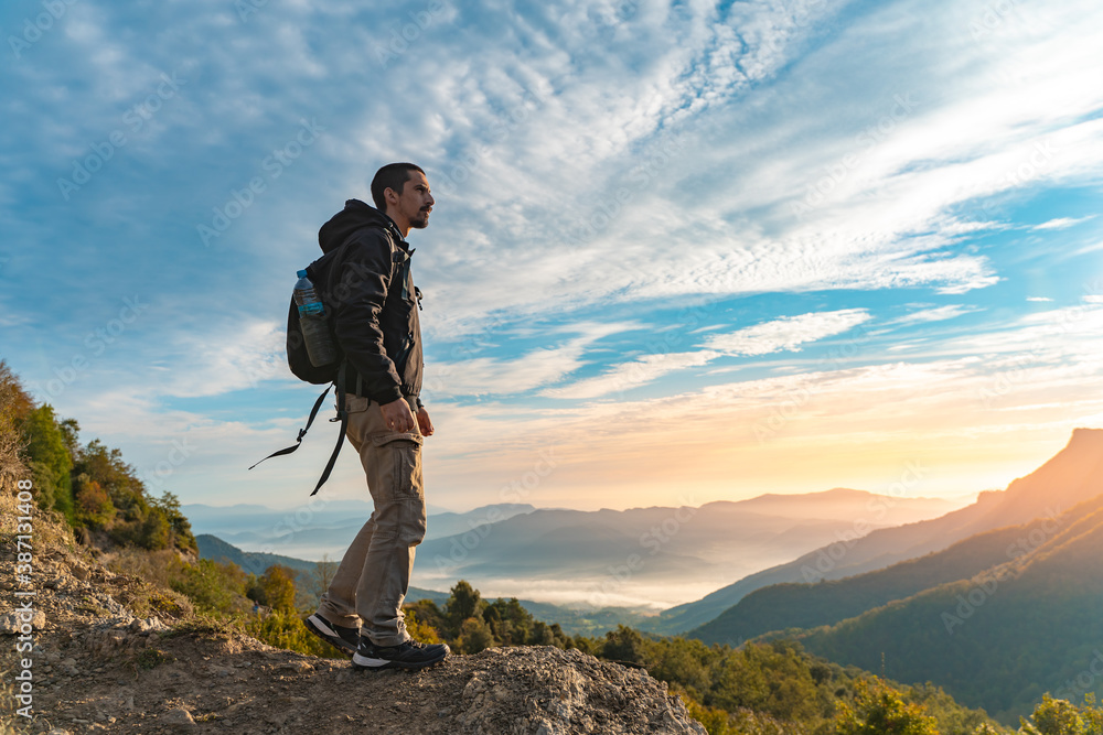 Foto Stock Handsome young man traveler hiking in mountains. Adventure solo  traveling lifestyle. Wanderlust adventure concept. Active weekend vacations  wild nature outdoor. Autumn fall forest. | Adobe Stock