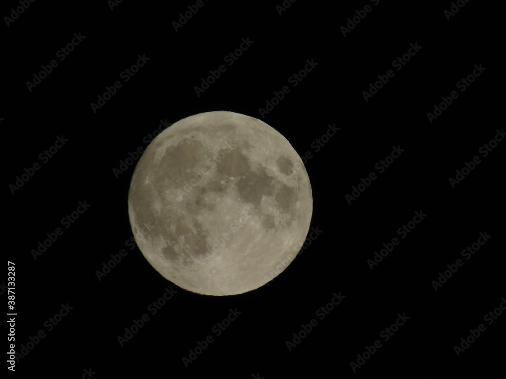 Genova, Italy - 09/25/2020: An amazing photography of the full moon over the city of Genova by night with a great clear sky in background and some stars
