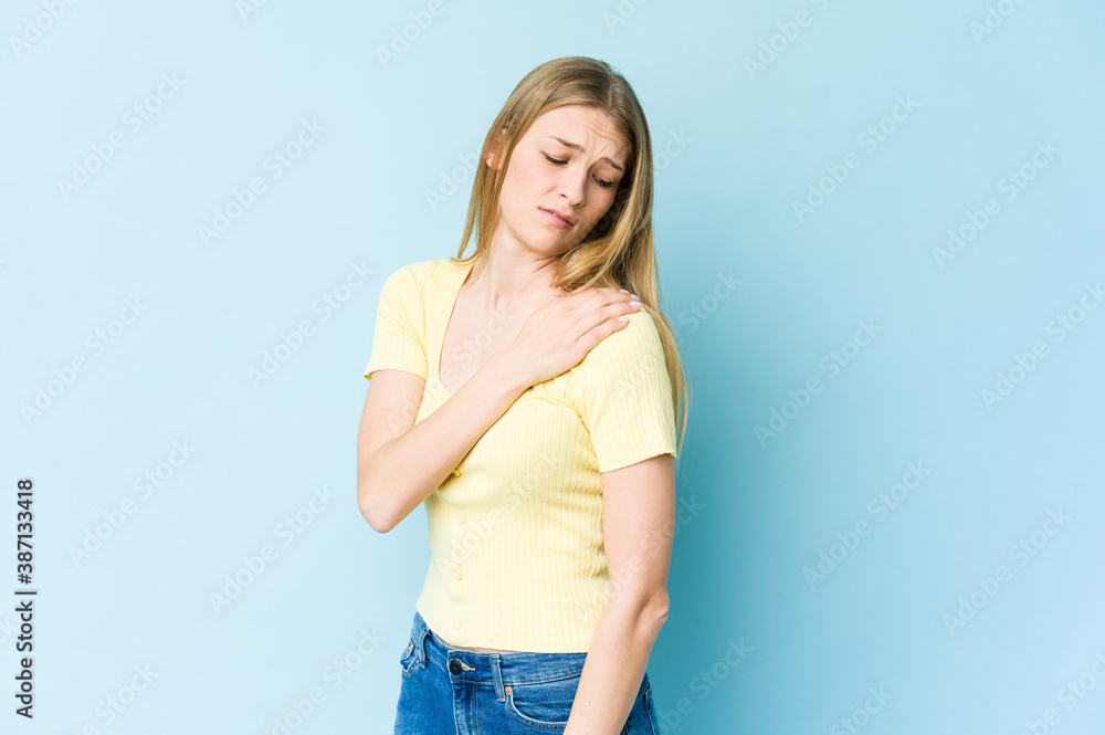 Young blonde woman isolated on blue background having a shoulder pain. Young blonde woman isolated on blue background having a shoulder pain.