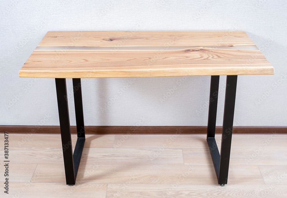 Wooden stylish table made of solid wood with epoxy resin on the background of the floor and wall. overall plan Wooden stylish table made of solid wood with epoxy resin on the background of the floor and wall. overall plan