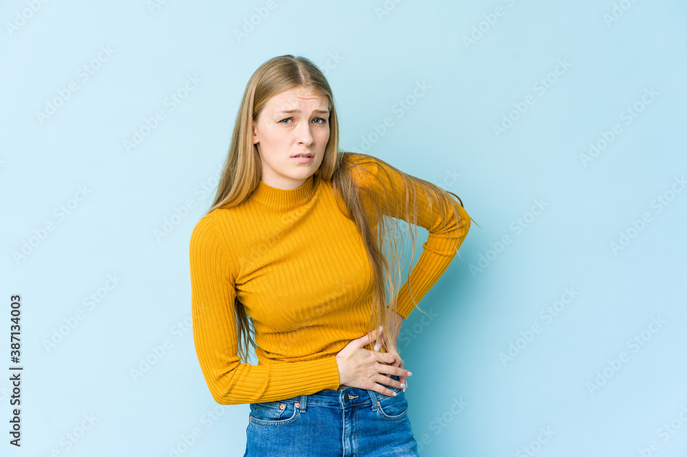 Young blonde woman isolated on blue background having a liver pain, stomach ache. Young blonde woman isolated on blue background having a liver pain, stomach ache.