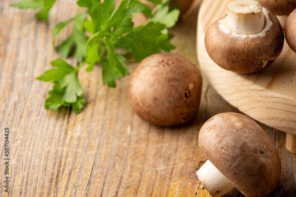 Close-up of portobello mushrooms and parsley on rustic wooden table, with selective focus, horizontal, with copy space