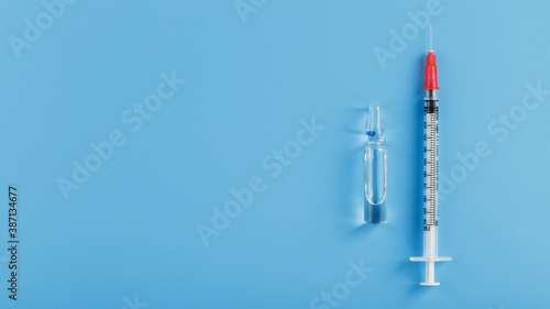 Syringes and ampoule with the vaccine against the Virus from diseases on a blue background.