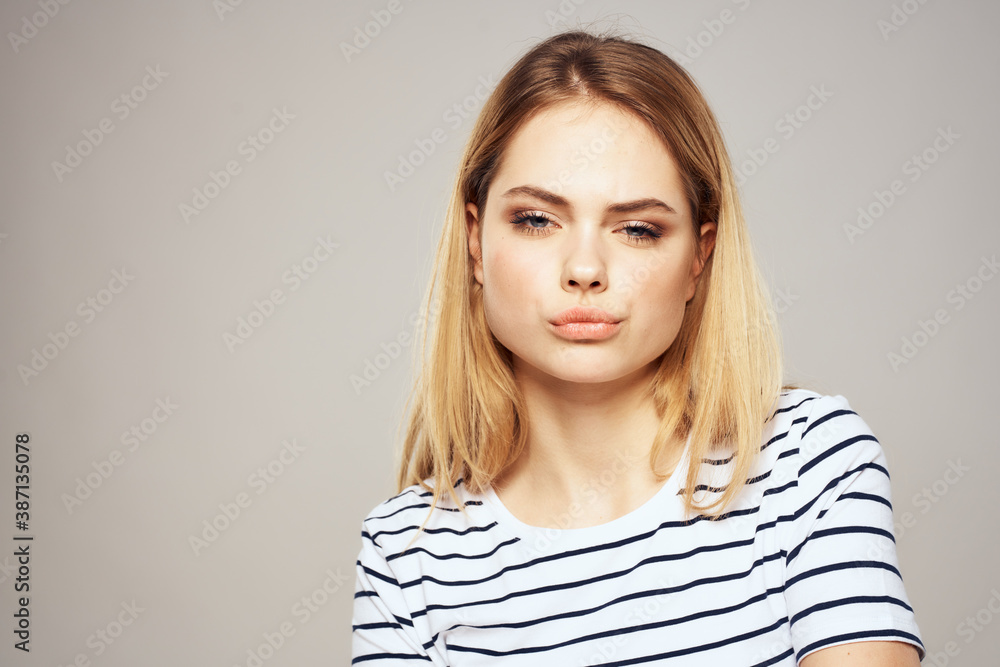 Emotional blonde woman in striped t-shirt lifestyle facial expression close-up Emotional blonde woman in striped t-shirt lifestyle facial expression close-up