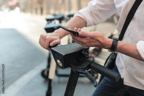 Man hands holding smartphone unlocking e-scooter