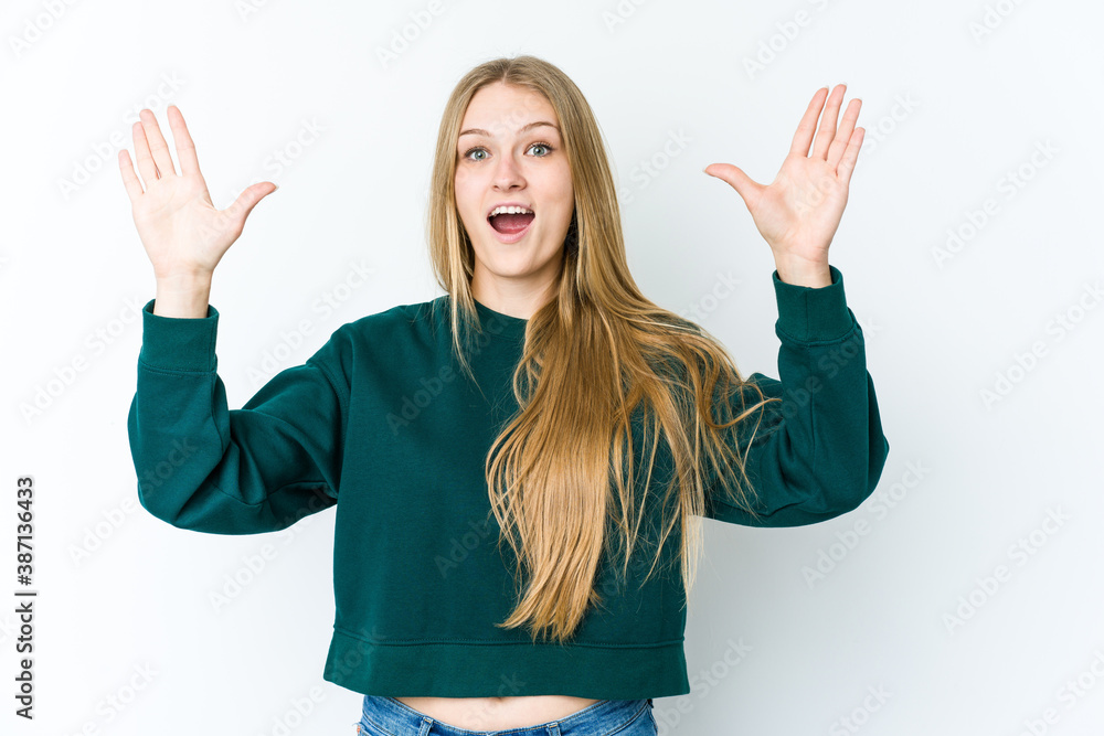 Young blonde woman isolated on white background receiving a pleasant surprise, excited and raising hands. Young blonde woman isolated on white background receiving a pleasant surprise, excited and raising hands.