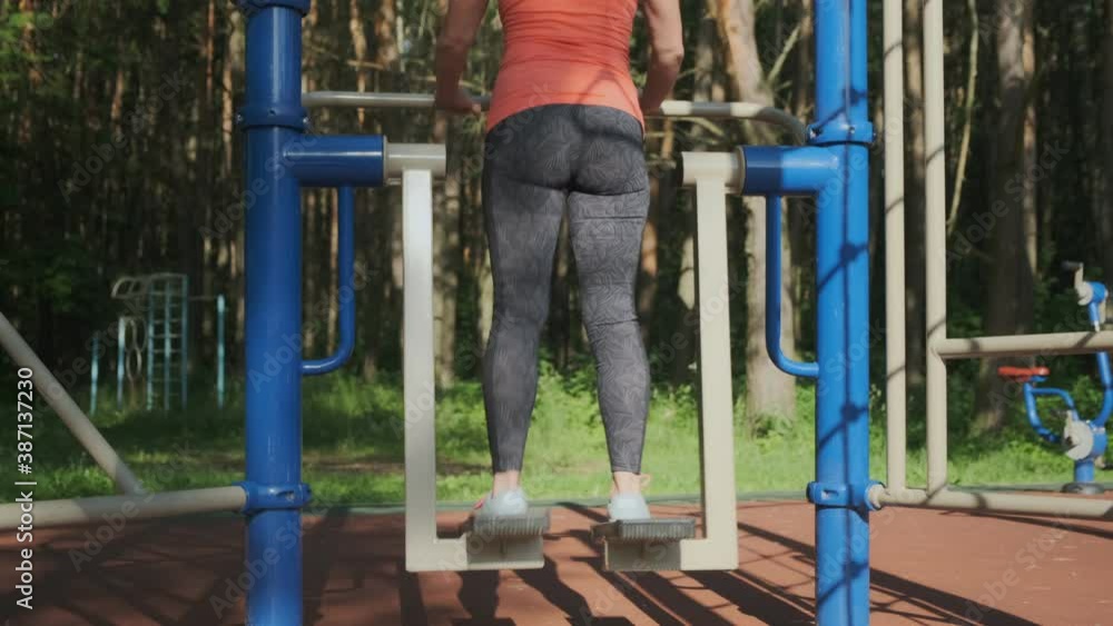 woman is engaged in fitness outdoors on simulator at sports ground. woman is engaged in fitness outdoors on simulator at sports ground.
